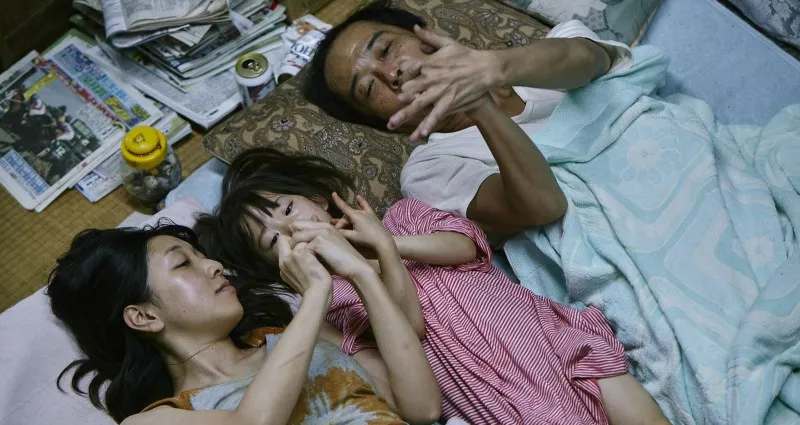 In foto Osamu(Lily Franky) e Nobuyo (Sakura Ando) con la piccola Yuri( Miyu Sasaki) in un'iconica scena del film