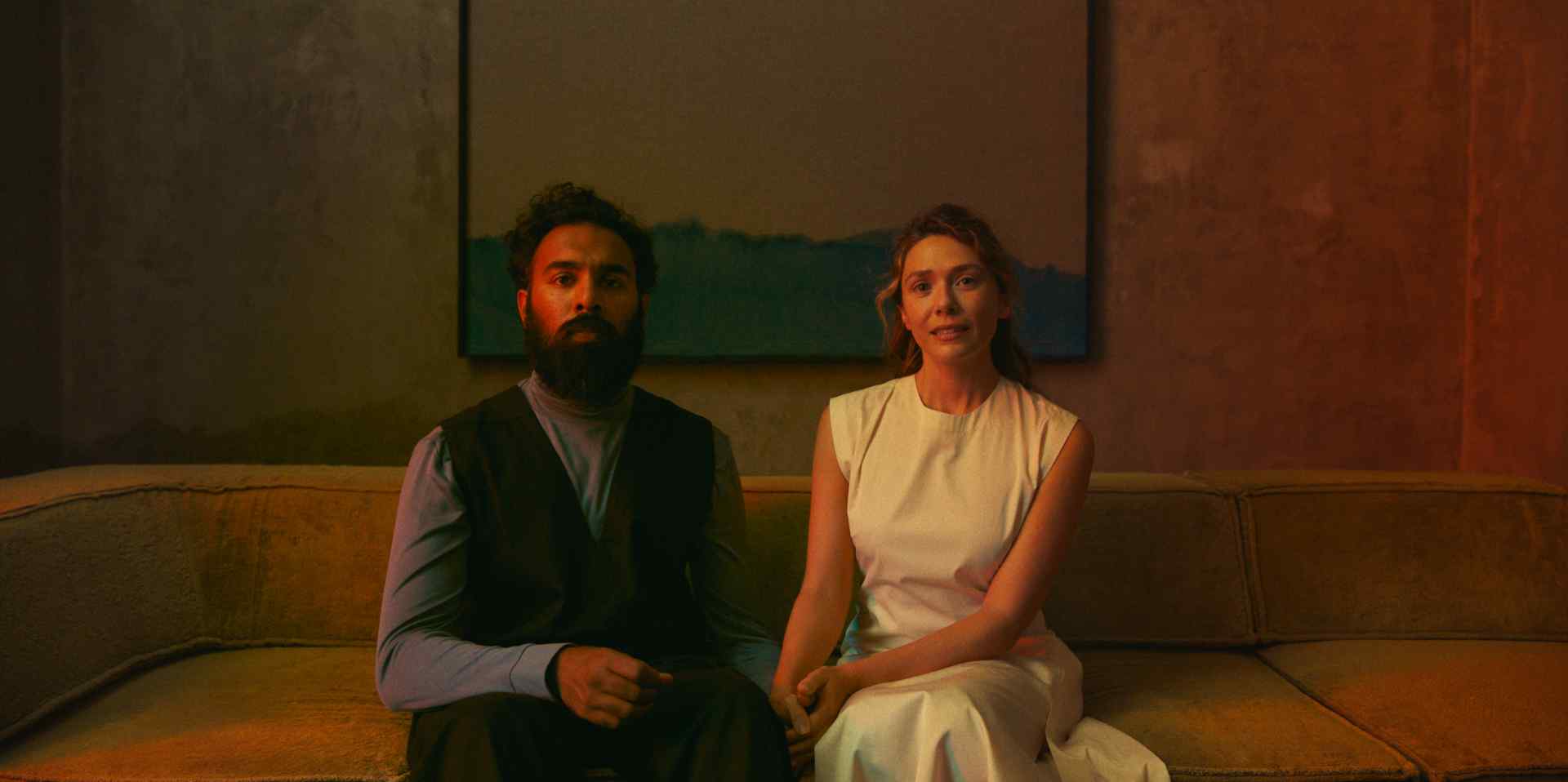 Himesh Patel and Elizabeth Olsen in THE ASSESSMENT, a Magnolia Pictures release. Photo credit: Magnus Jønck. © 2024 Number 9 Films Assessment Limited, TA Co-Production GmbH, ShivHans Productions, LLC, TA2022 Investors, LLC, Tiki Tāne Pictures, LLC. Photo courtesy of Magnolia Pictures.